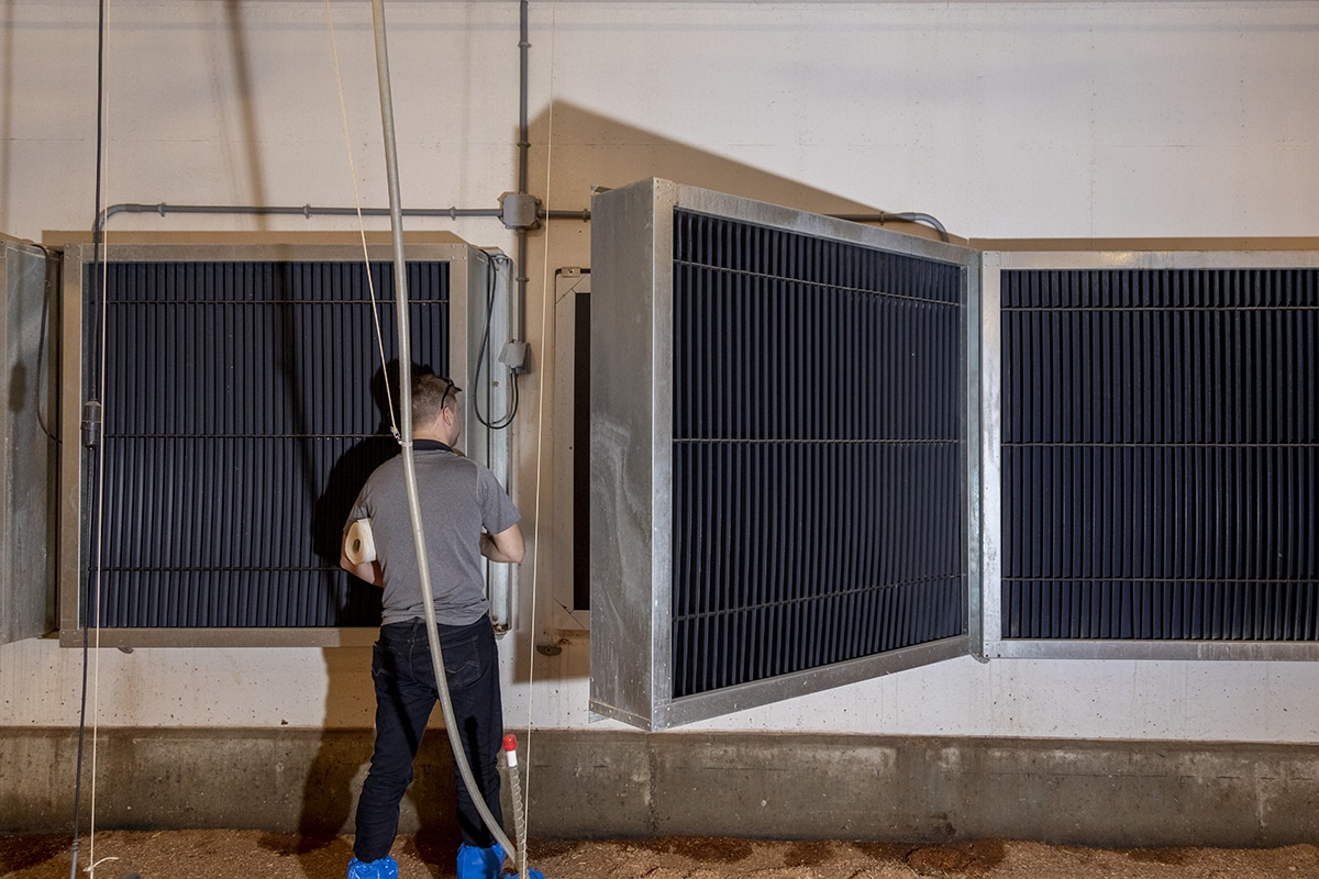 Individual inspecting or working on large open metal utility boxes with electrical components.