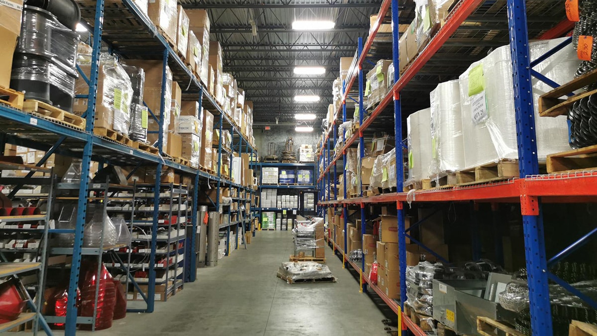 Tall metal shelving units stocked with various boxes and products, arranged in parallel rows.